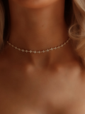 Micro hydrangea pavé necklace in gold, worn on model’s neckline, showcasing the intricate design and sparkling details of the piece.