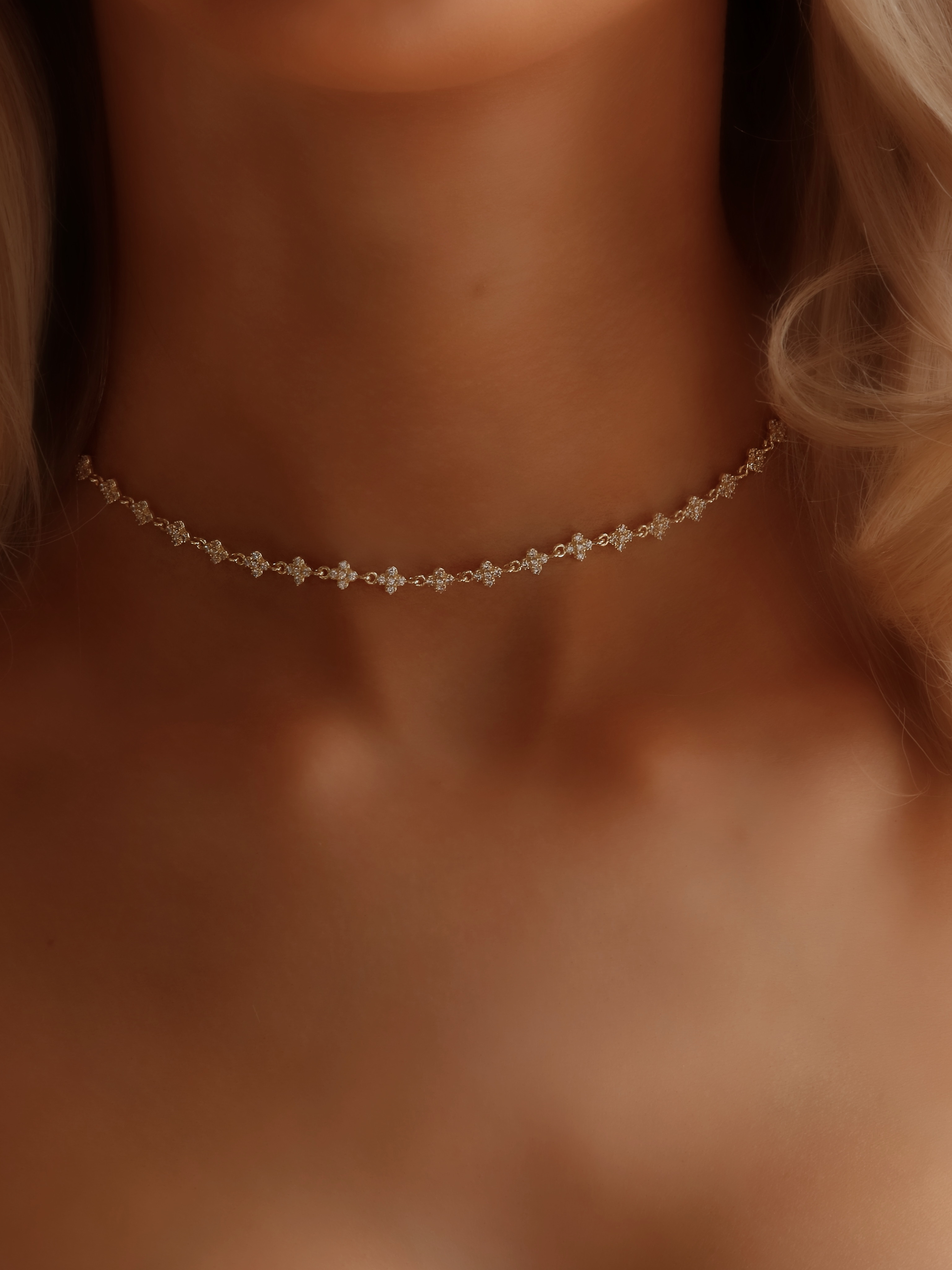Micro hydrangea pavé necklace in gold, worn on model’s neckline, showcasing the intricate design and sparkling details of the piece.