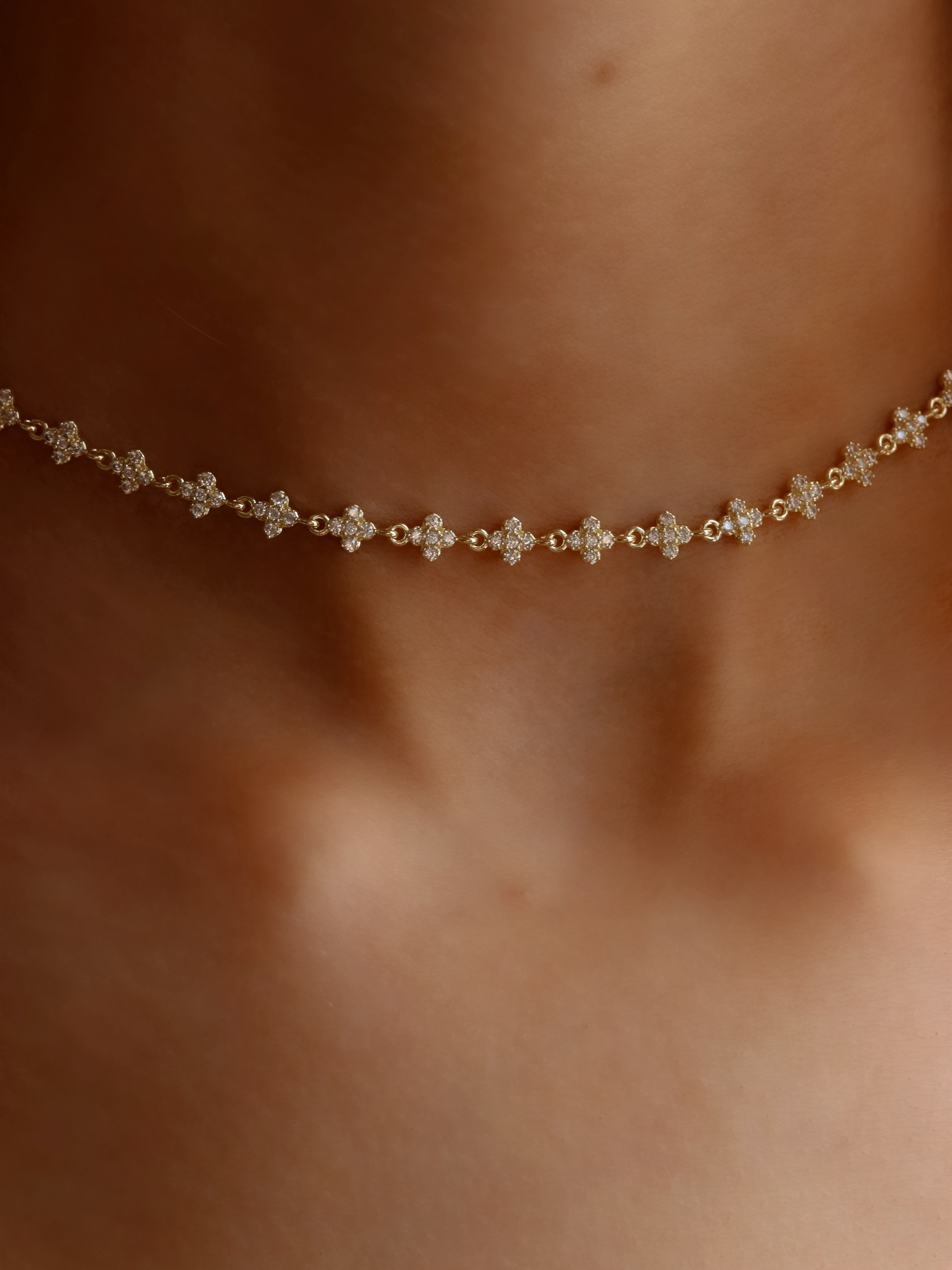 Close-up of micro hydrangea pavé necklace in gold, highlighting the intricate flower petal details on the pendant, worn on model’s neckline.