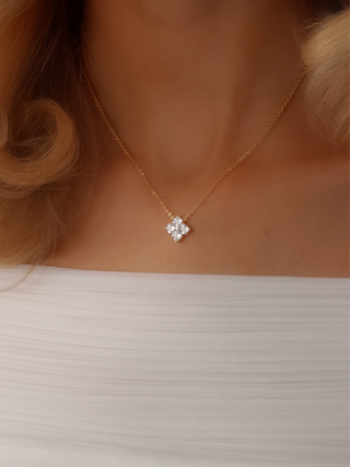 Close-up shot of the Mini Crystal Hydrangea Necklace on a model's neckline, with the delicate CZ stone catching the light against the top of a white dress
