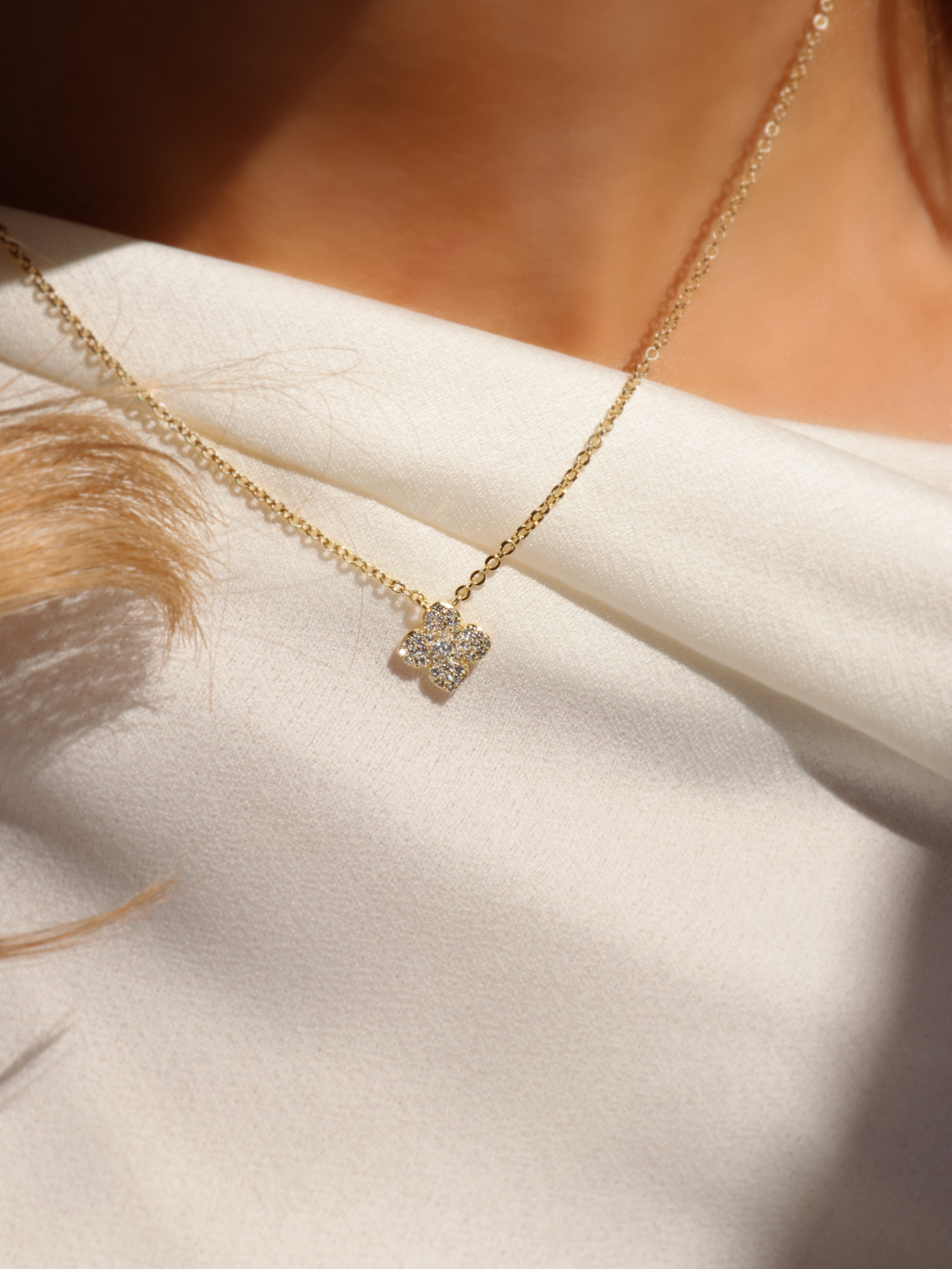 Gold plated Mini Hydrangea necklace with pavé flower pendant photographed in natural light on cream fabric, highlighting texture and sparkle