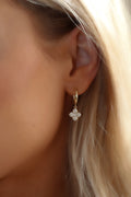 Mini Hydrangea hoop earrings in gold plating, featuring a delicate dangling hydrangea flower with sparkly cubic zirconia stones, worn by model, luxurious yet affordable jewellery brand.