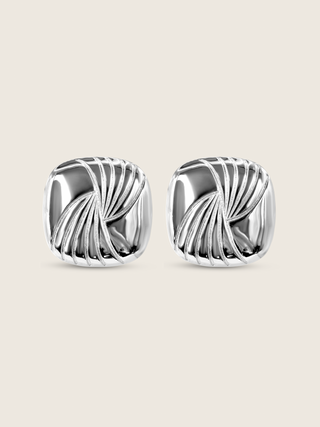 Flatlay of the Miranda earrings, featuring bold sculptural curves in high-polish sterling silver with white gold plating, designed with an 80s-inspired silhouette for a statement-making accessory.