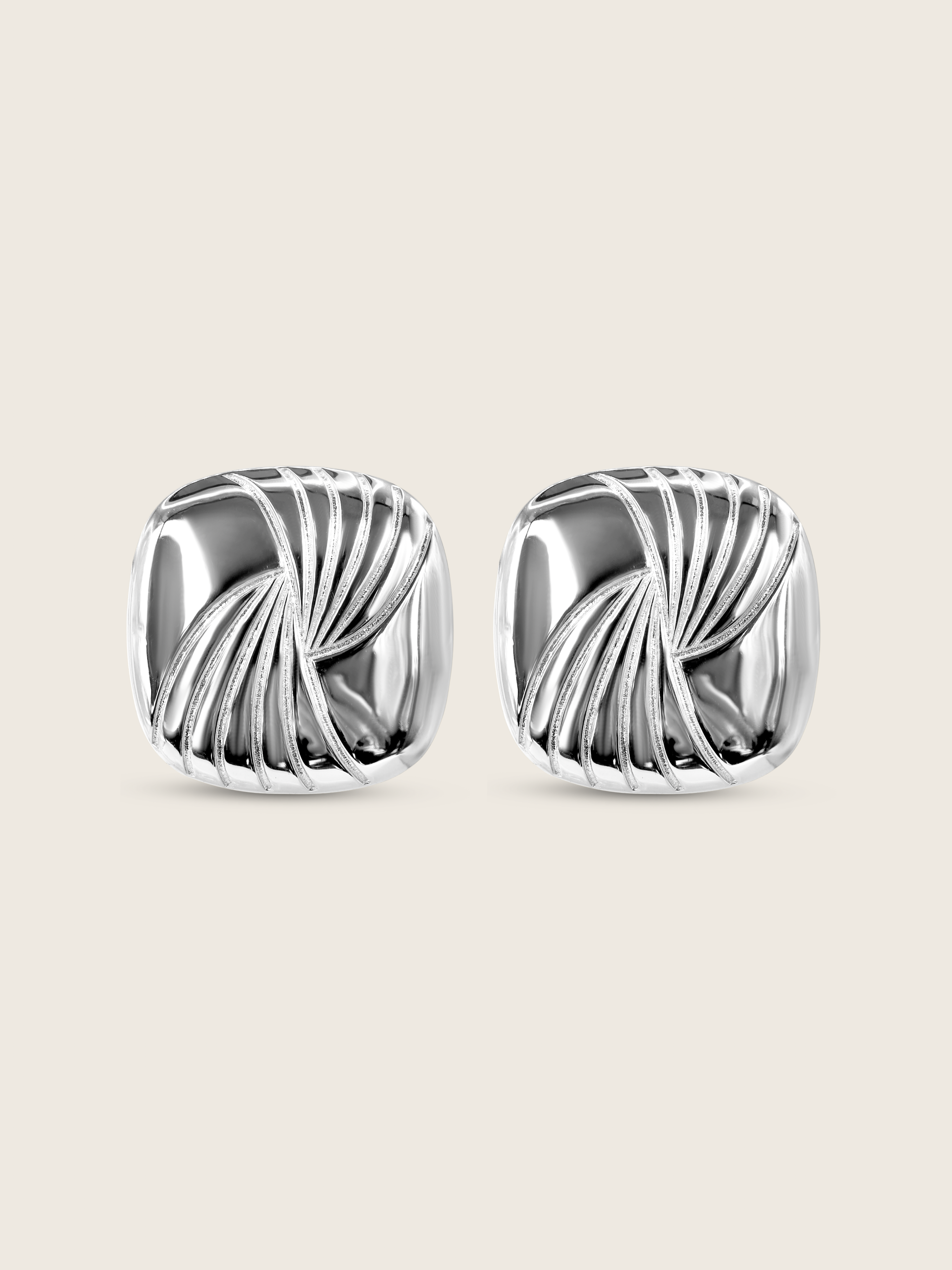 Flatlay of the Miranda earrings, featuring bold sculptural curves in high-polish sterling silver with white gold plating, designed with an 80s-inspired silhouette for a statement-making accessory.