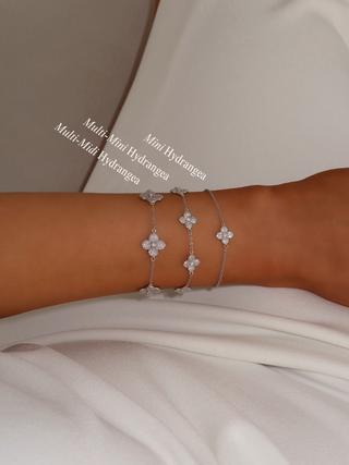 Stacked view of three White Gold plated Hydrangea bracelets on model’s wrist, including Mini, Multi Mini, and Multi Midi styles