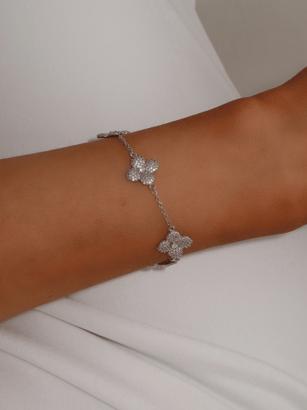 Multi Midi Hydrangea bracelet in premium White Gold plating worn on wrist, featuring delicate pavé floral motifs and fine chain