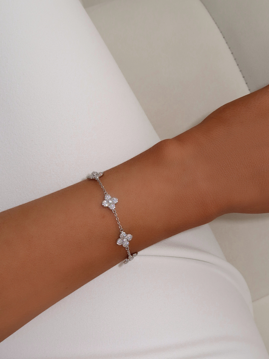 Close-up of Multi Mini Hydrangea bracelet in White Gold plating worn on wrist, with floral pavé charms spaced along a fine chain