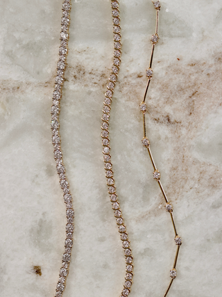 Gold plated Nova tennis bracelet, Estelle bracelet and Astra bracelet with cubic zirconia stones flatlay on marble background