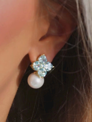video of the crystal hydrangea earrings and necklace in aqua worn on a model with a white background, showing how it catches the light