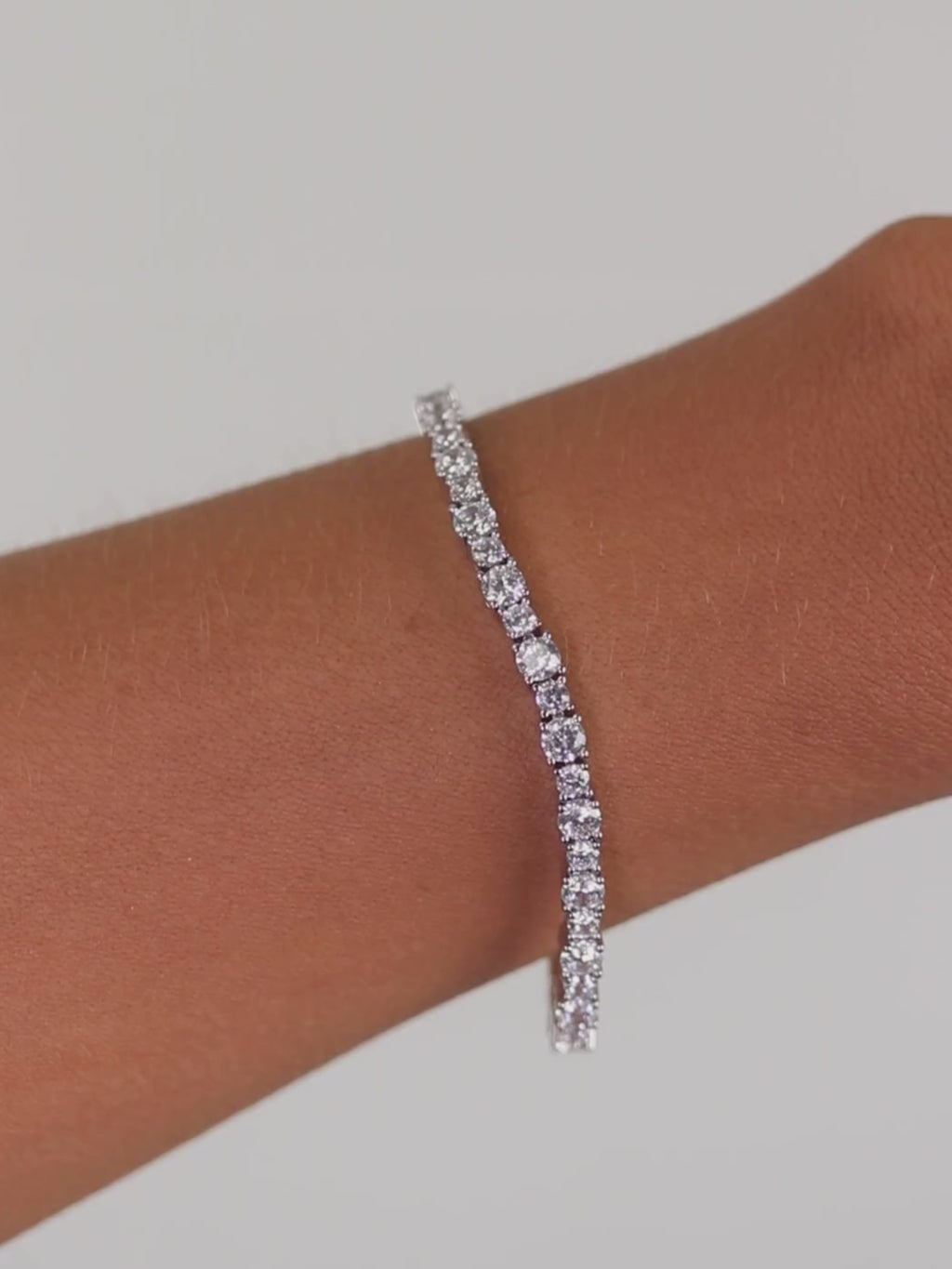Nova tennis bracelet in premium white gold plating with continuous row of cubic zirconia stones shown on model wrist