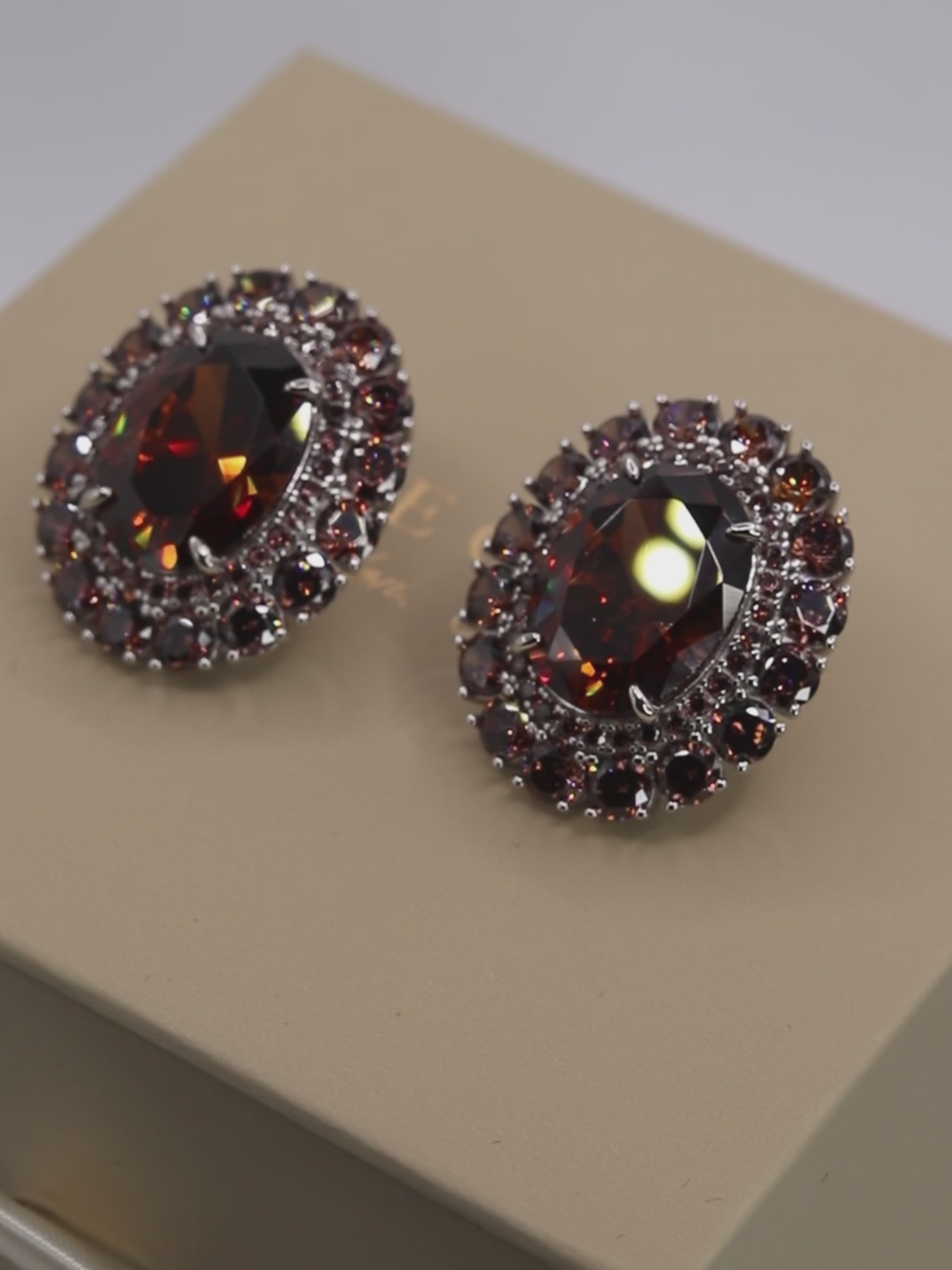 Rotating video of Diana earrings in white gold with wine coloured centre stones and sparkling cubic zirconia halo