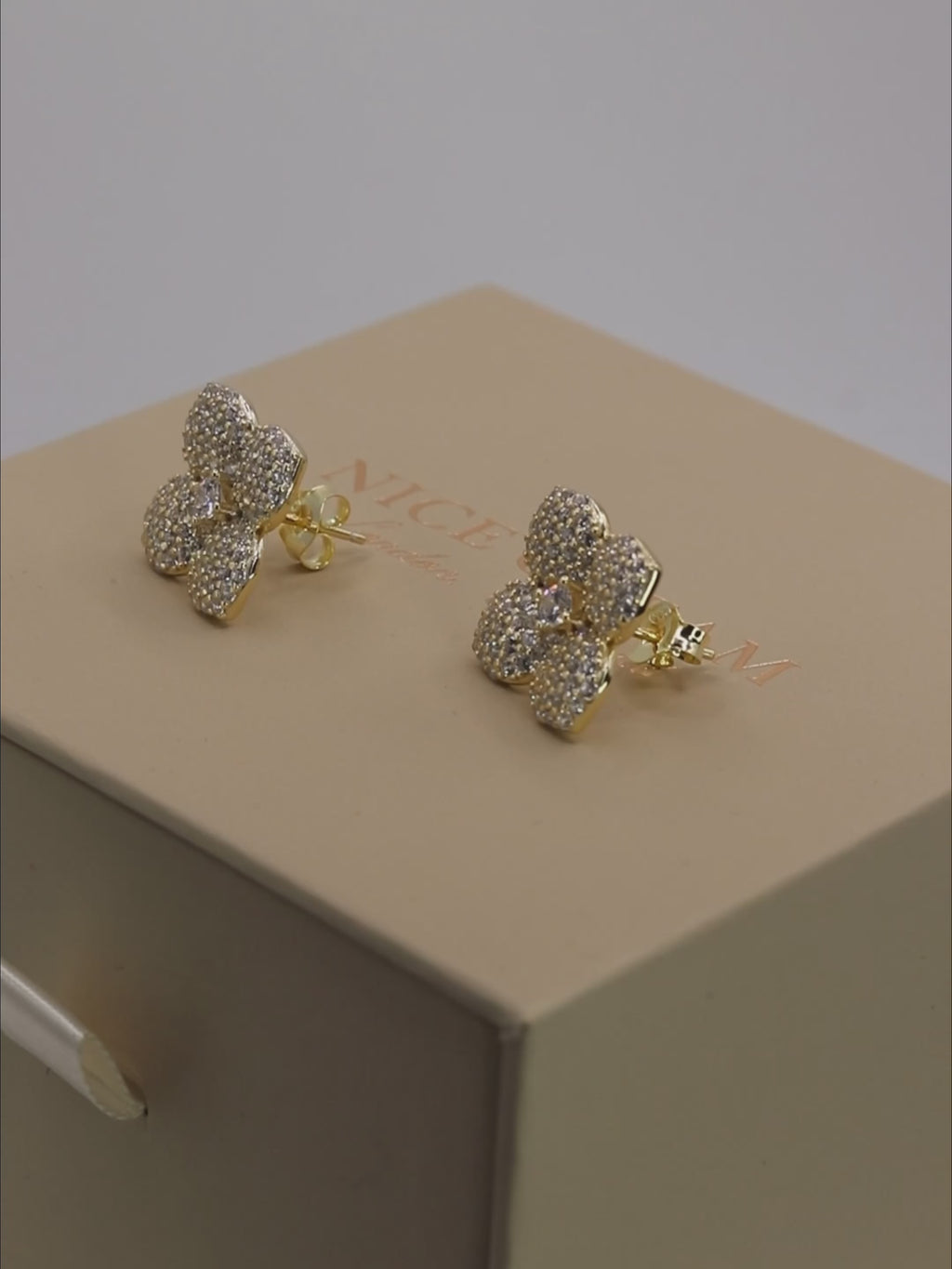 Gold plated Hydrangea stud earrings with pavé stones rotating on a display carousel, showcasing sparkle and floral detail