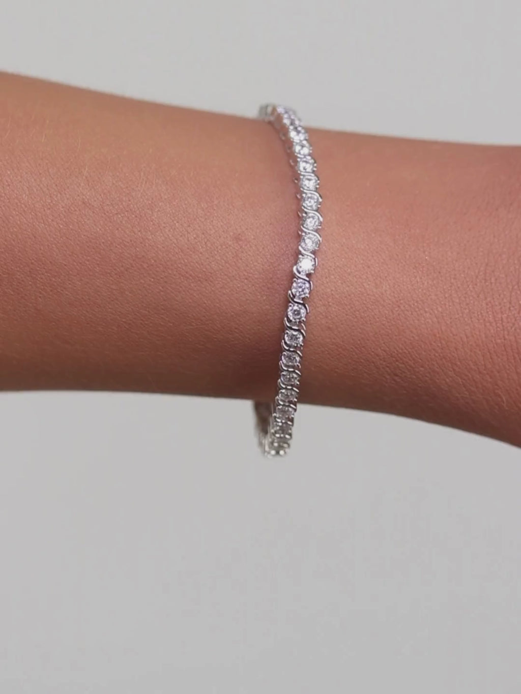 Estelle tennis bracelet premium white gold plated brass with cubic zirconia stones in wave S link design shown on model wrist