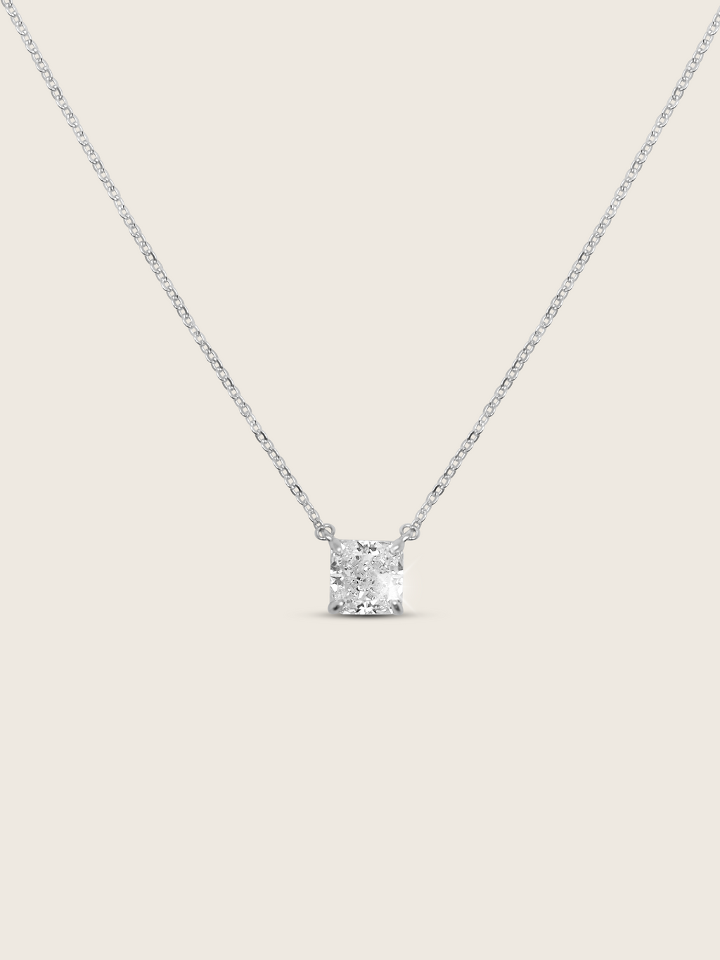 Regina necklace featuring a precisely cut square CZ stone set on a delicate sterling silver and white gold plated chain, displayed flat-lay on a white background to depict it's sparkle