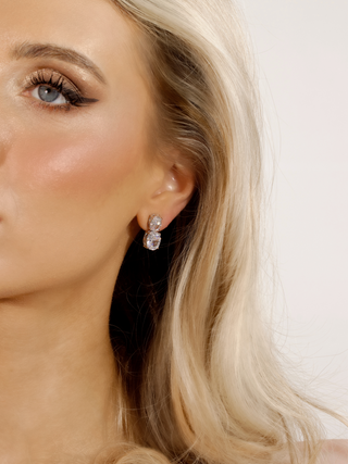 oval stone dangle design earrings, worn in ear with a white background, showcasing sparkle