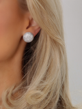 Close-up of model wearing round white gold plated stud earrings encrusted with pavé cubic zirconia stones