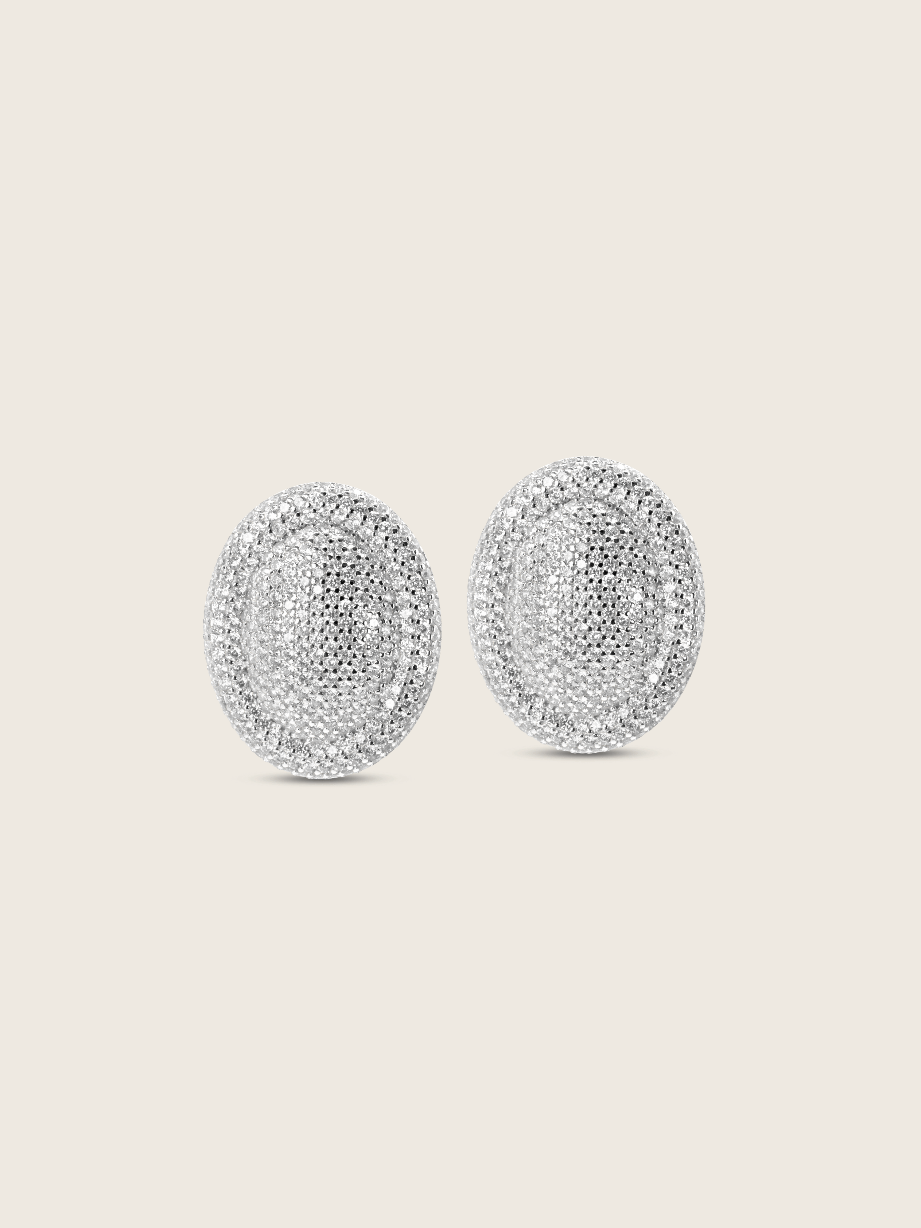 White gold plated Gigi pavé oval stud earrings fully covered in clear CZ stones, shown on white background. Statement earrings with all-over sparkle and curved silhouette.