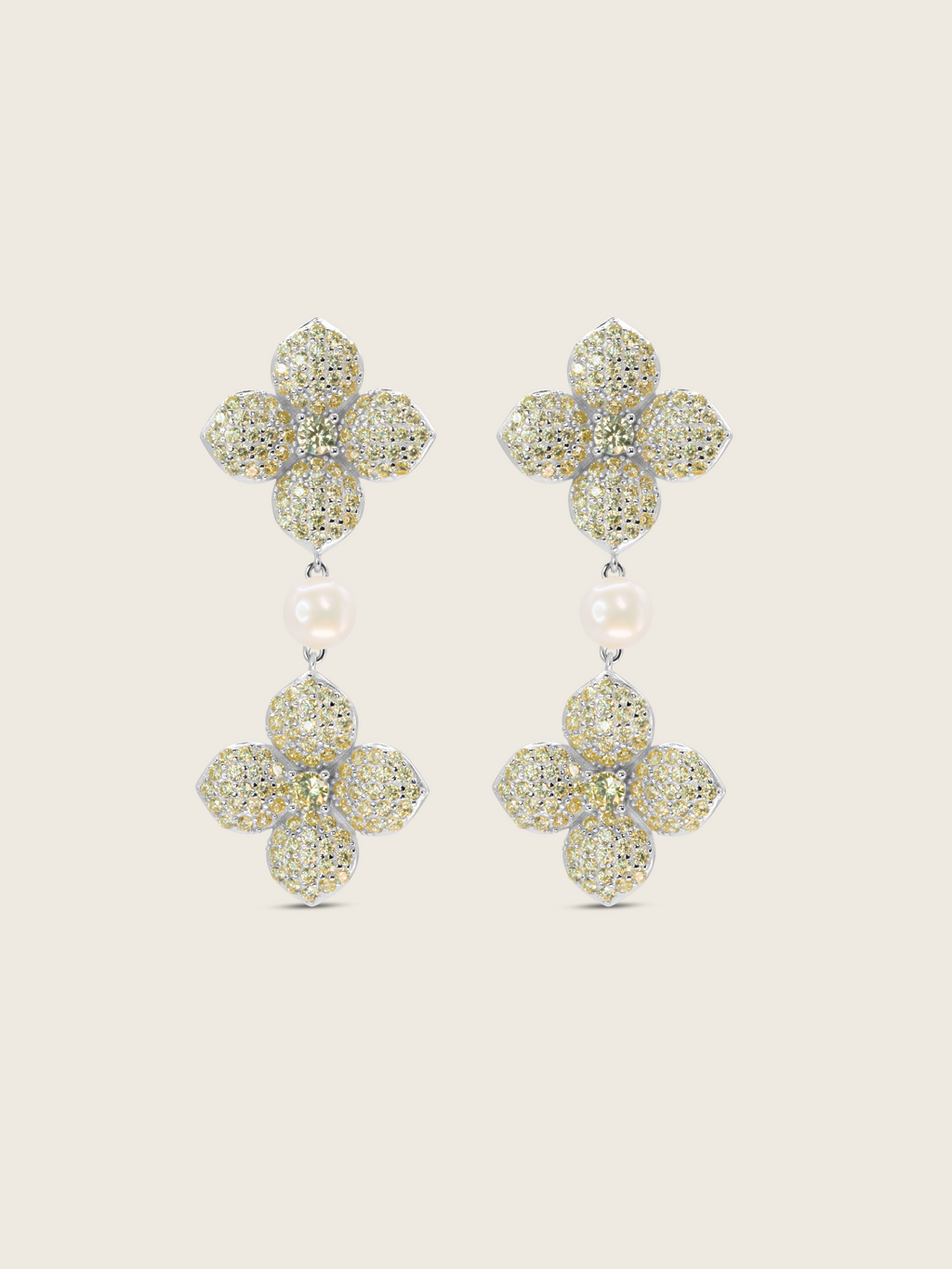 White gold plated hydrangea dangle earrings with yellow cubic zirconia stones and freshwater pearl on white background. Elegant floral drop earrings with sparkly detailing.