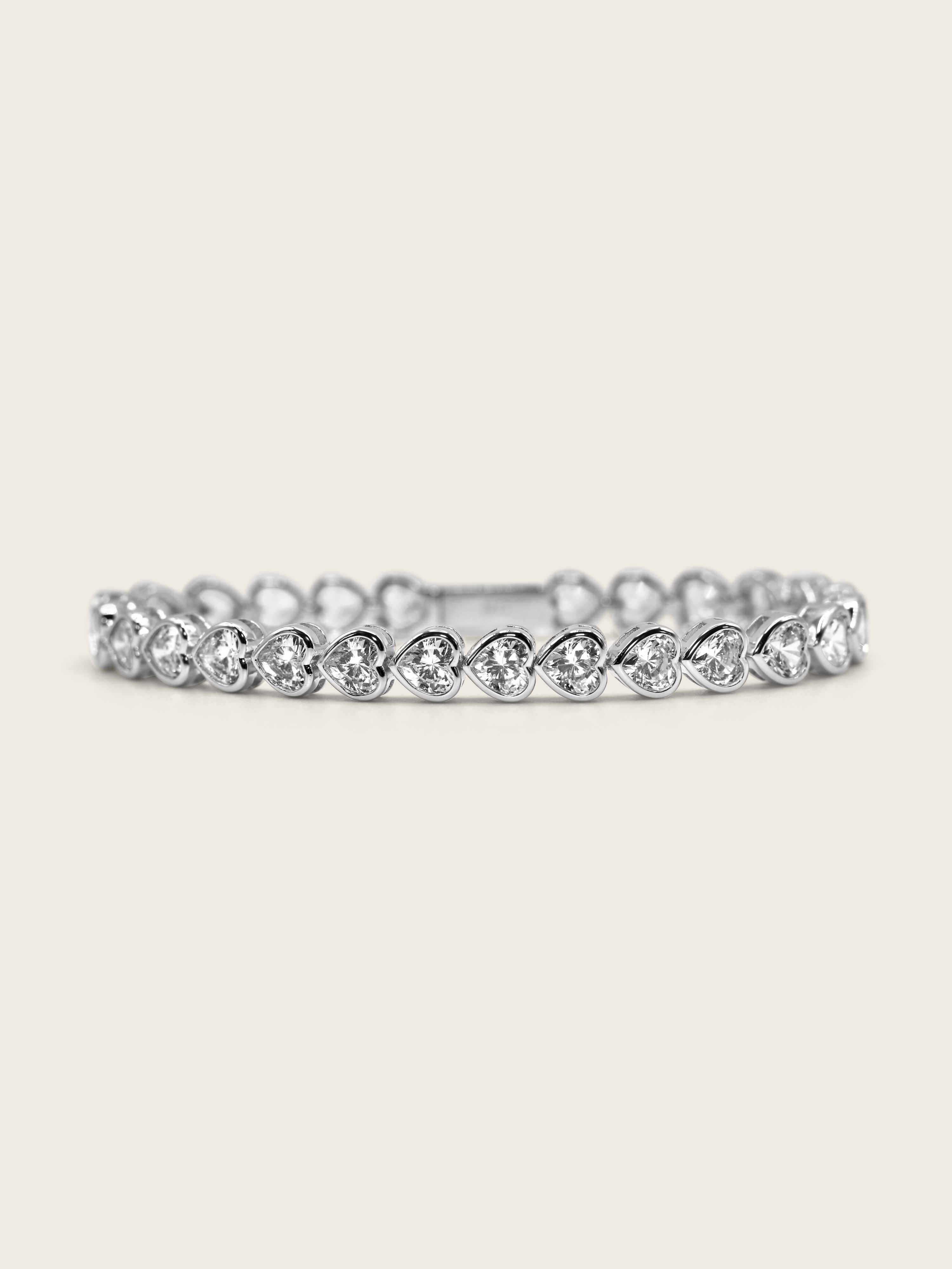 White gold plated heart tennis bracelet with bezel-set heart-cut cubic zirconia stones, a romantic and elegant twist on a classic silhouette