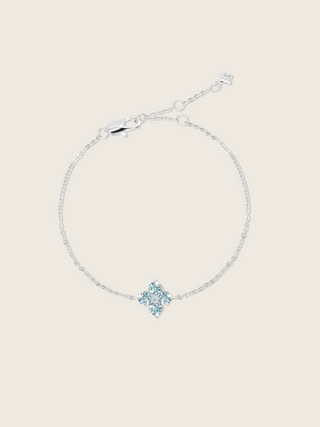 a flat lay of the white gold plated mini crystal hydrangea bracelet with aqua stones, sparkling on a neutral background 