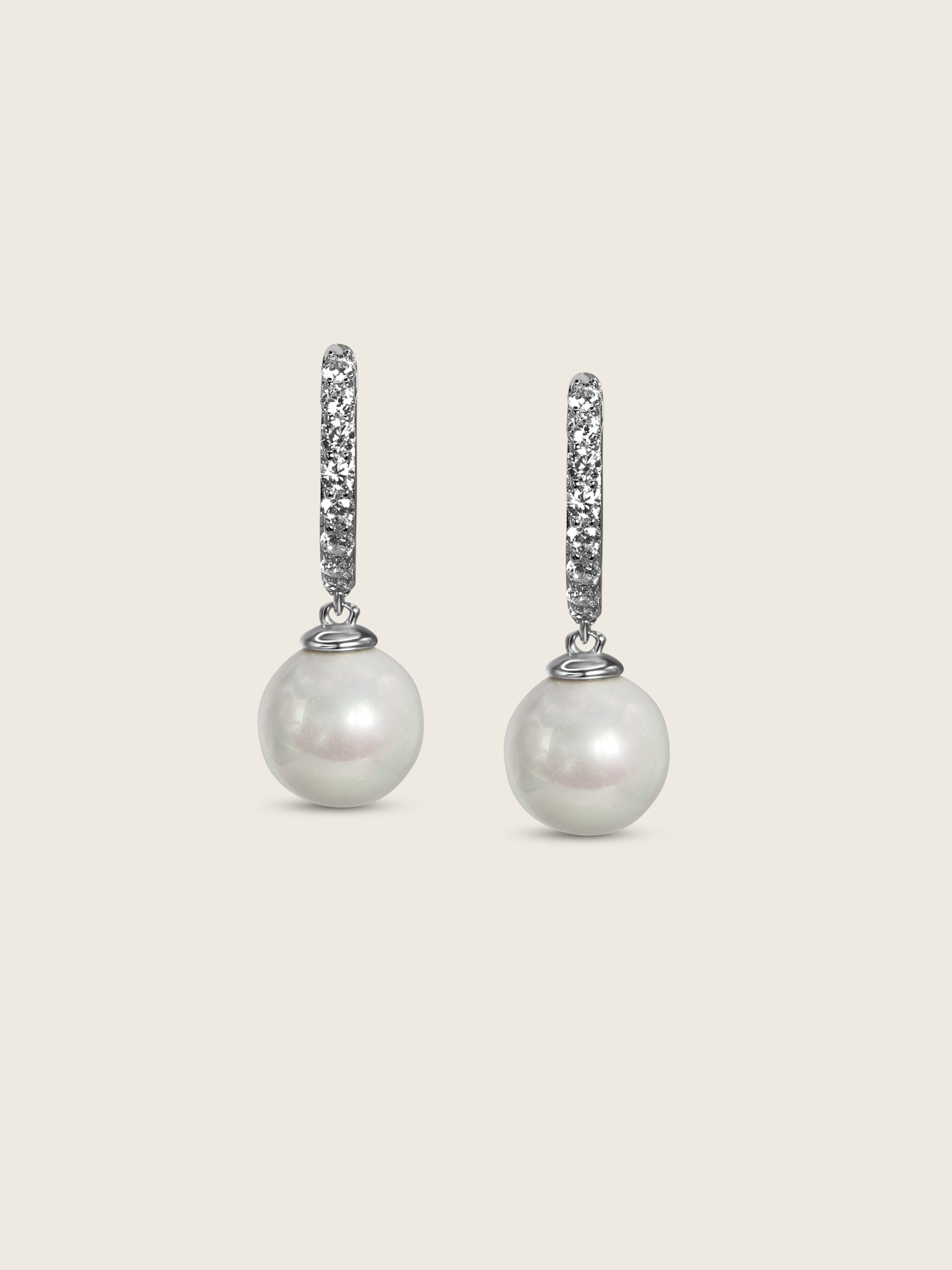 White gold drop earrings with CZ-set hoops and round freshwater pearls, elegant flatlay on cream background